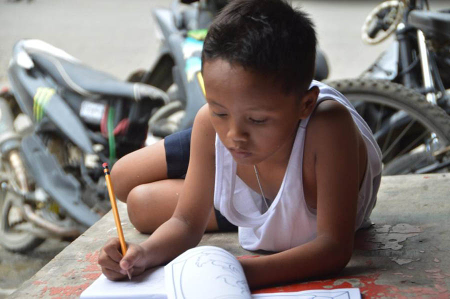 菲律宾男孩借麦当劳灯光街上写作业