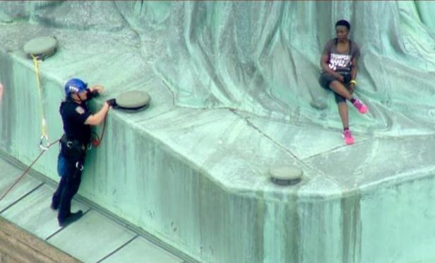 反对特朗普移民政策 美国独立日一女子爬上自由女神像基座抗议