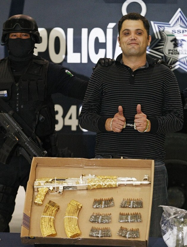 墨西哥毒枭落网竖起拇指供记者拍照 警方展示其镶金AK47