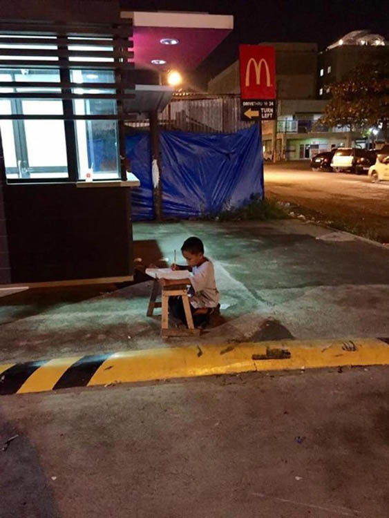 菲律宾男孩借麦当劳灯光街上写作业